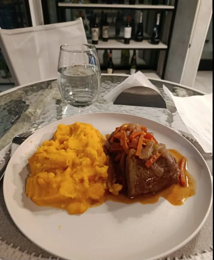 Vianda servida en plato: puré de calabaza y carne con cebolla y morrones